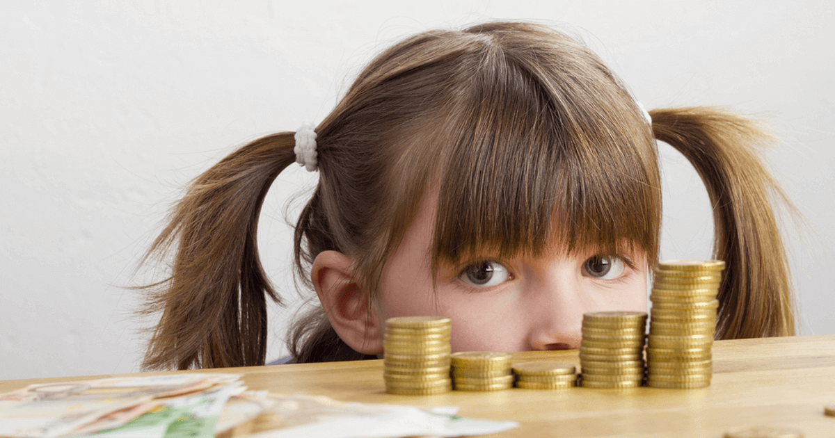Kleines Mädchen schaut über einige Geldtürmchen.